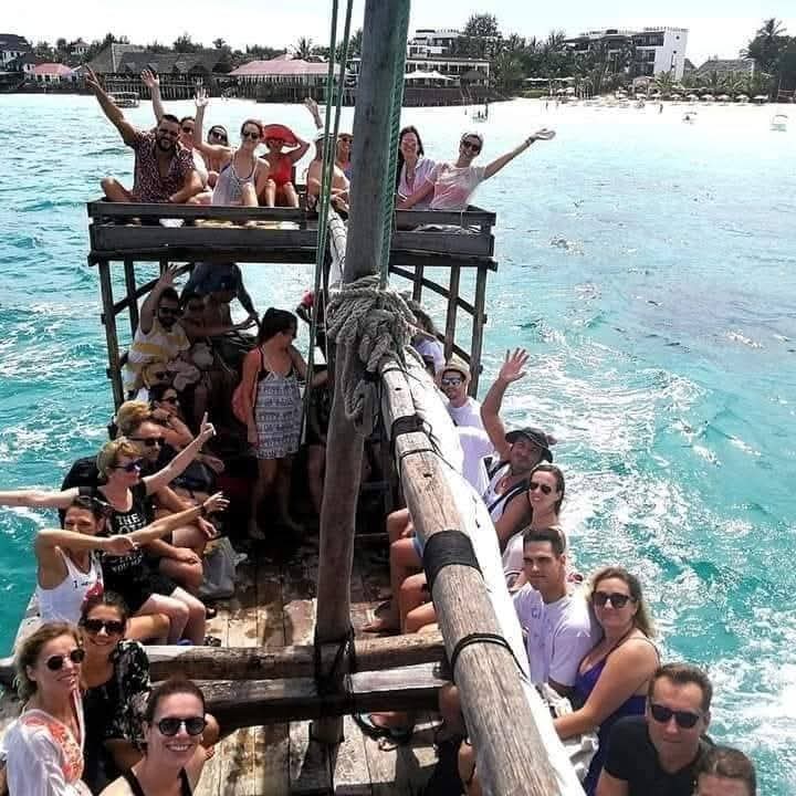 Group of guests waving from a traditional dhow boat