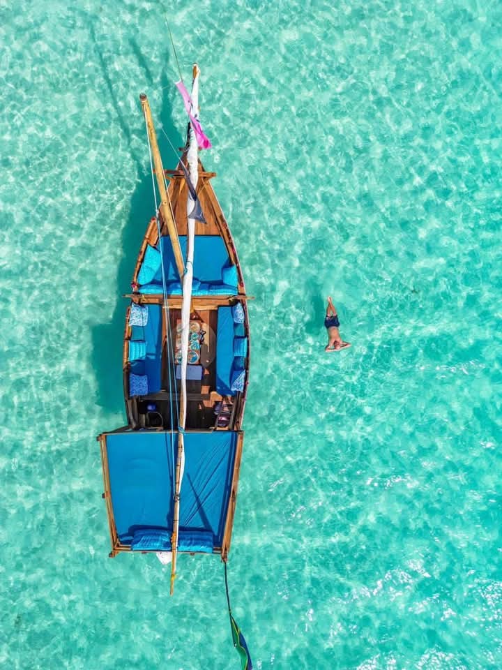 Aerial view of a traditional dhow boat in crystal clear turquoise water